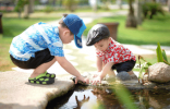 2 preschool-aged children exploring things in and around a small stream