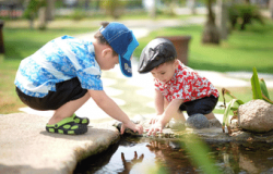 2 preschool-aged children exploring things in and around a small stream