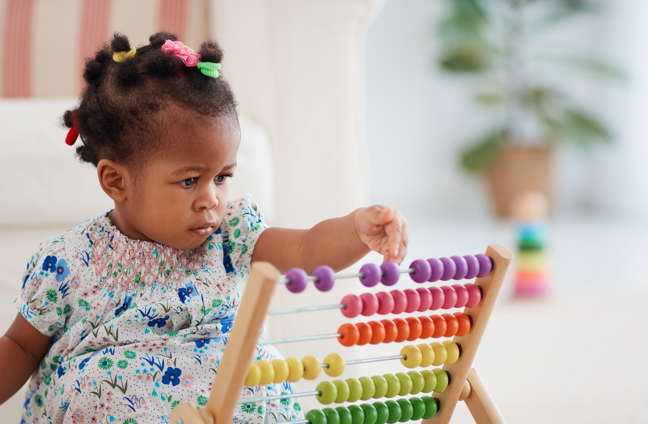 infant playing with colorful abacus toy