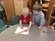 two boys are using a ruler for drawing