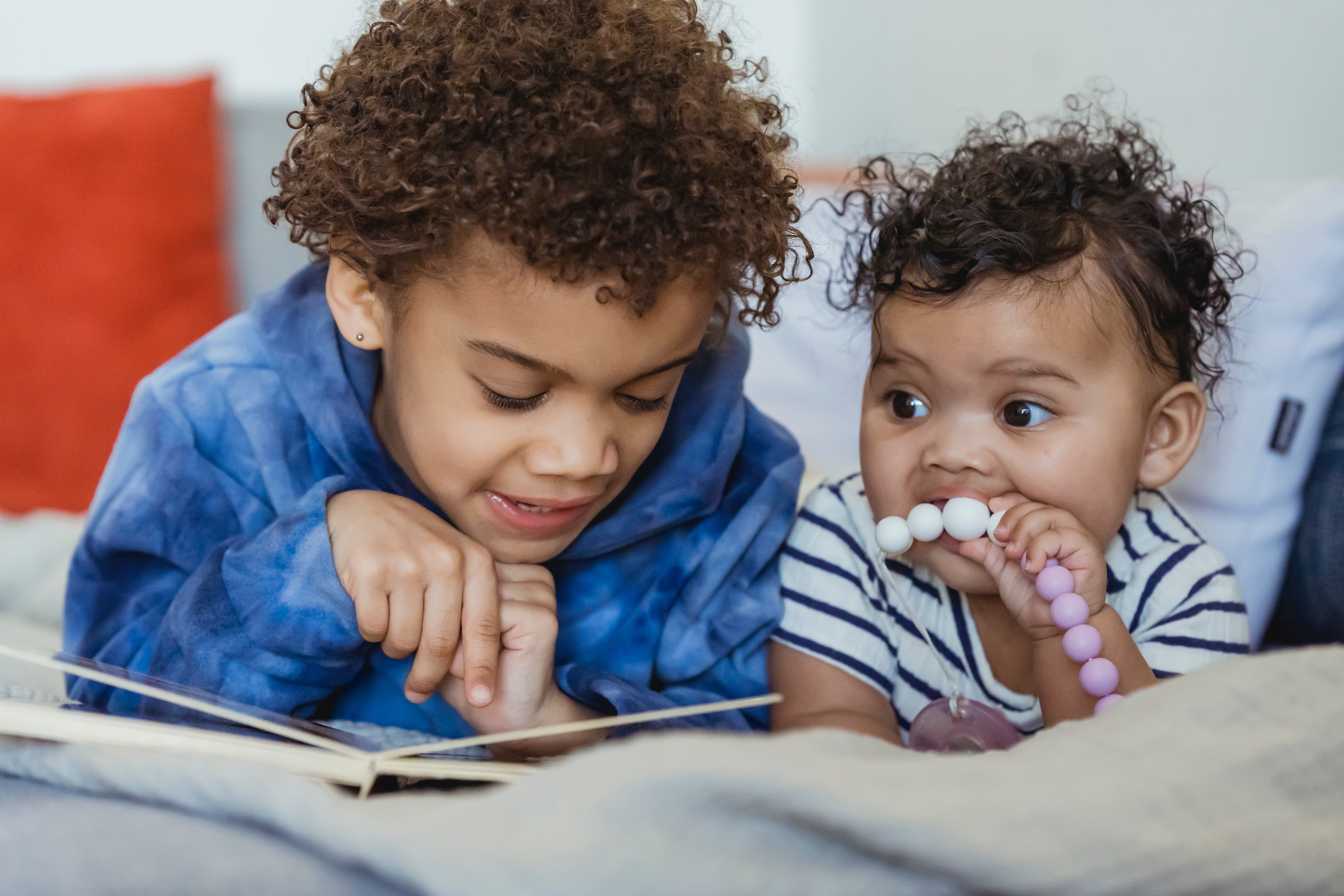 pexels-keira-burton-6623865 3 year old looking at a picture book with infant sibling